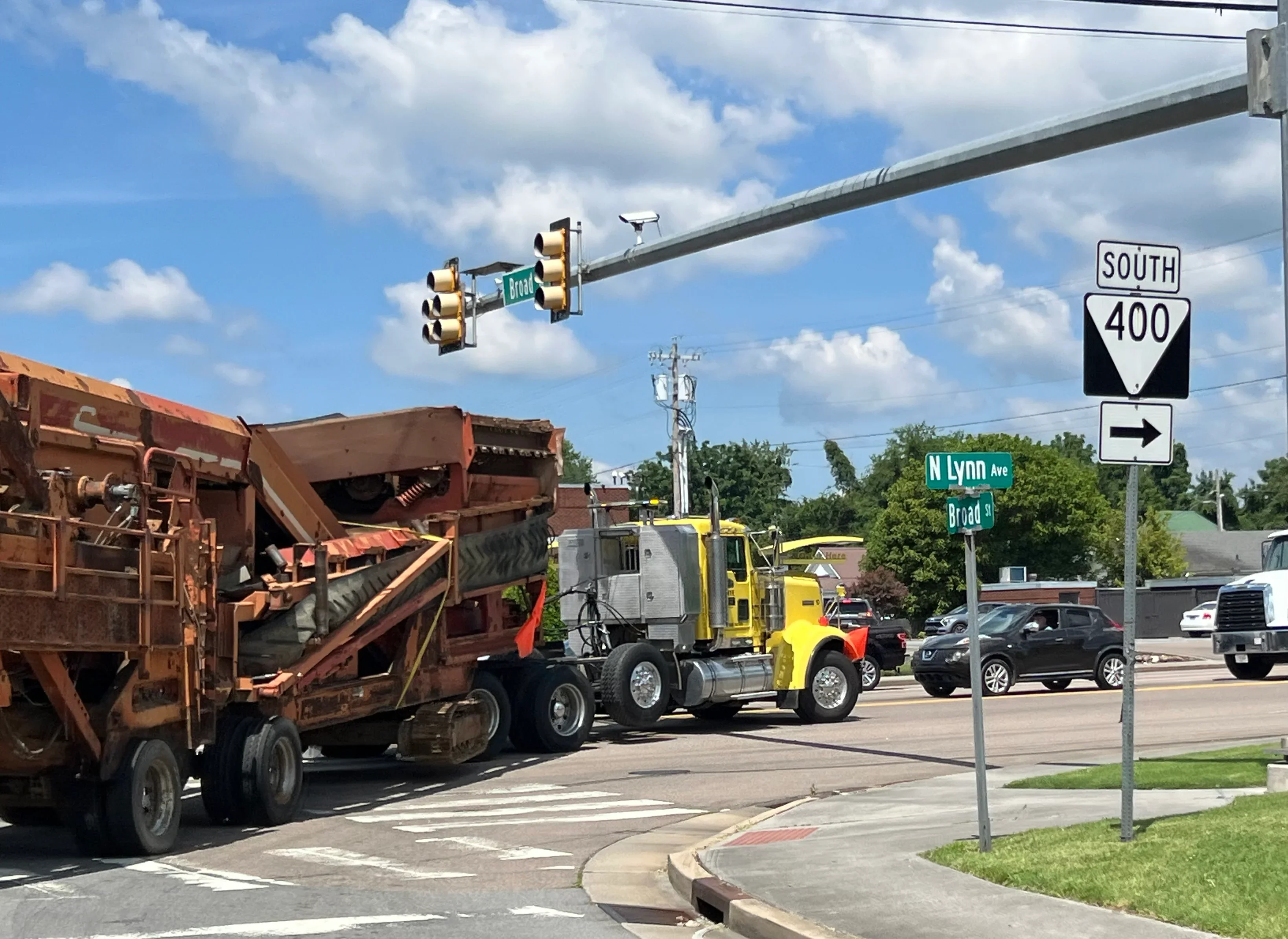 Yellow articulated hauler transporting heavy dump truck through intersection with traffic signals
