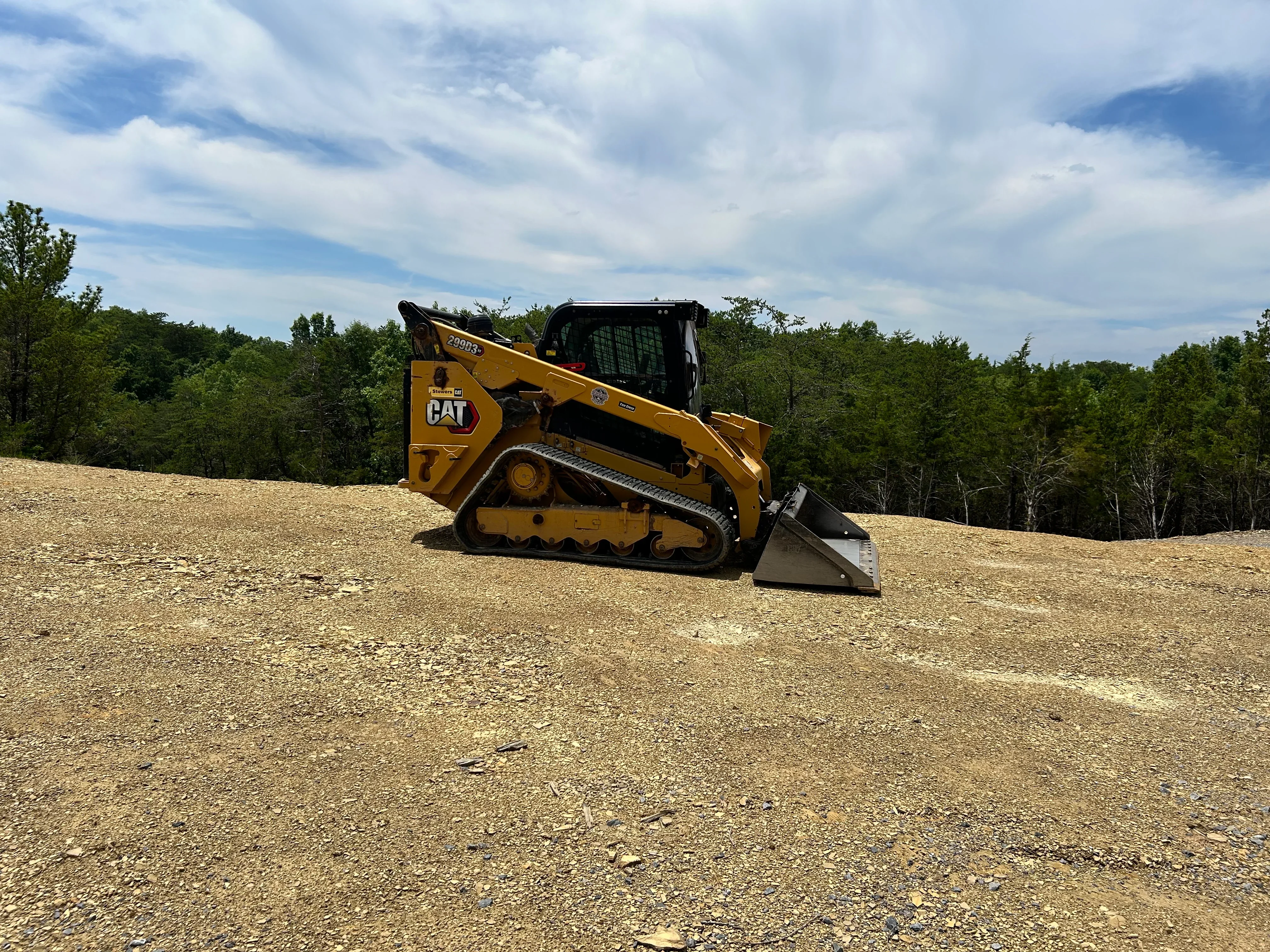 CAT track loader grading aggregate material on cleared construction site
